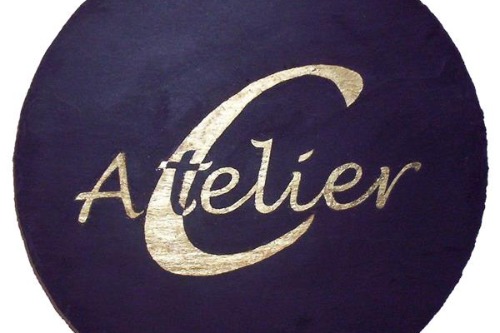 Logo Atelier in C in goud geschreven. 